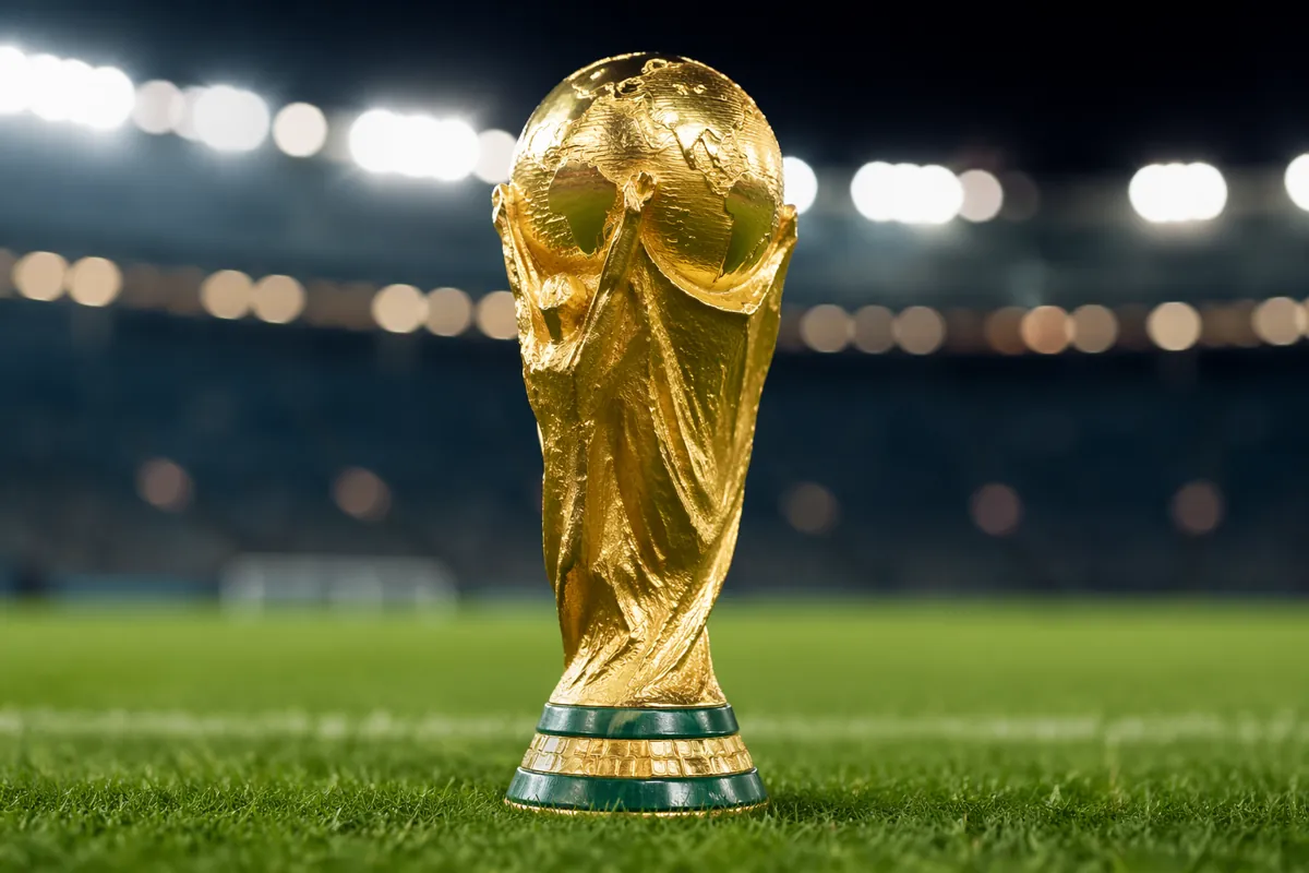 Close-up of the golden FIFA World Cup trophy placed on a neatly trimmed green football pit