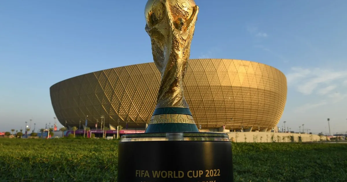Wide shot of a packed world cup football stadium at dusk, bright stadium lights illuminati