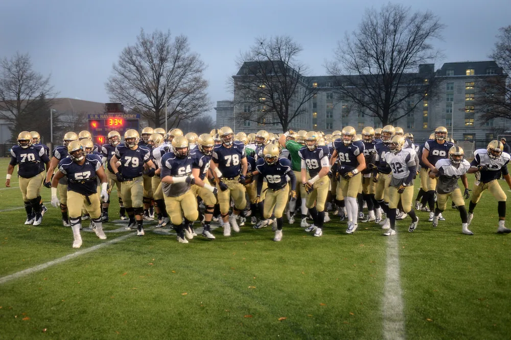 Wide shot of a football team huddling on the pitch during a break, blurred faces