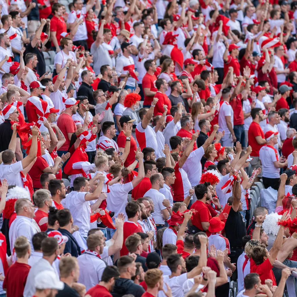 Wide shot of generic football fans wearing red and white colored fan merchandise