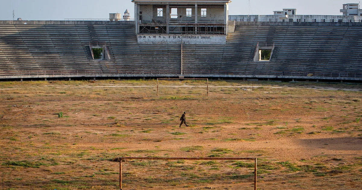Professional football stadium during golden hour, blurred generic football players warming