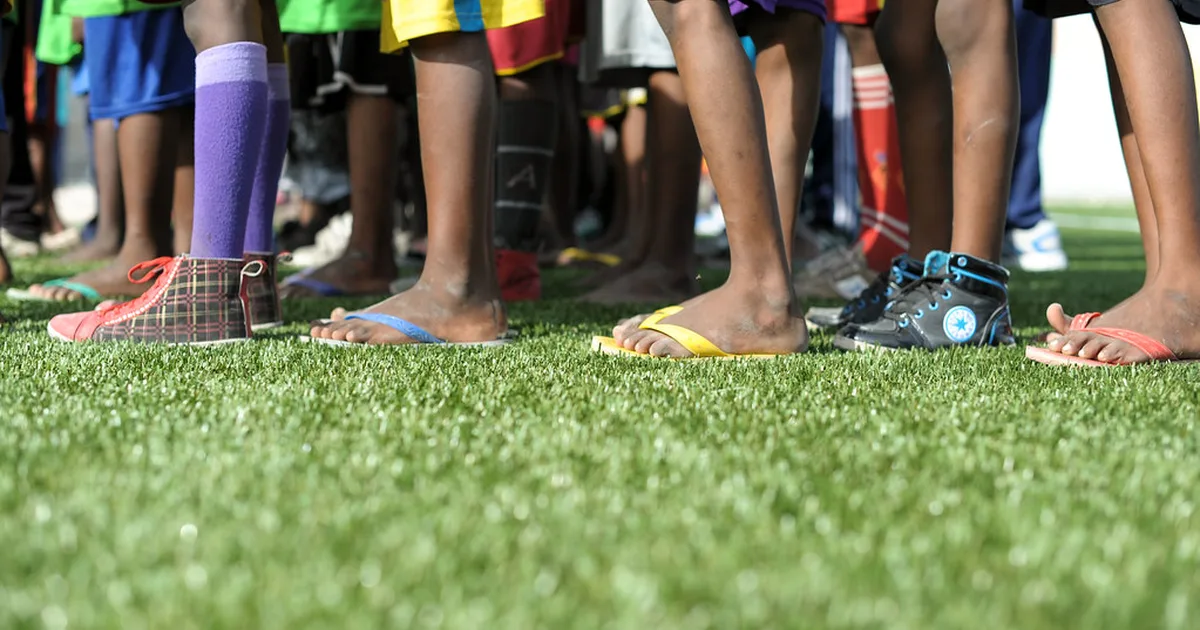 Wide shot of a bright outdoor football training pitch with blurred players in casual train