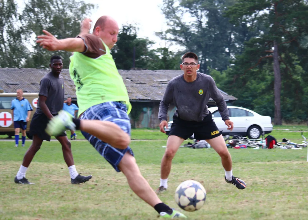 Football midfield action blurred silhouette, green grass pitch background, brigh