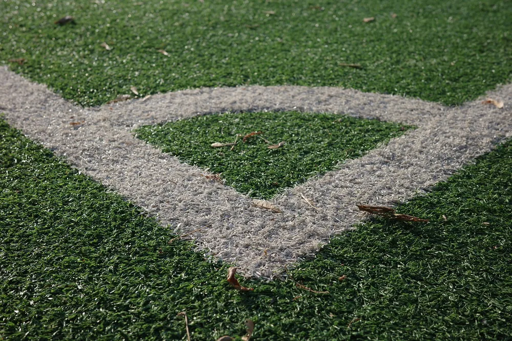 Close up of a generic football on a well-maintained green pitch, with blurred st