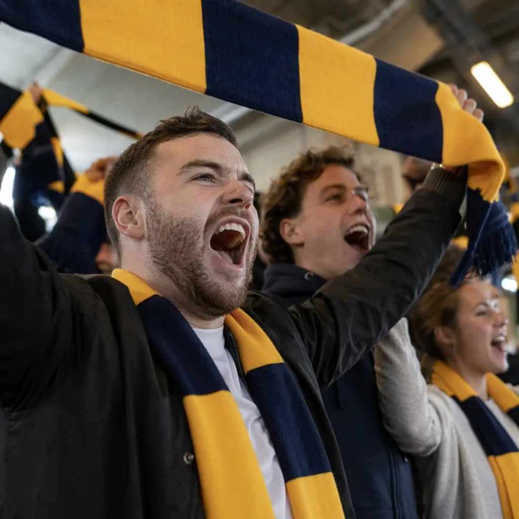 Close up of football fans holding generic team scarves and cheering in a stadium