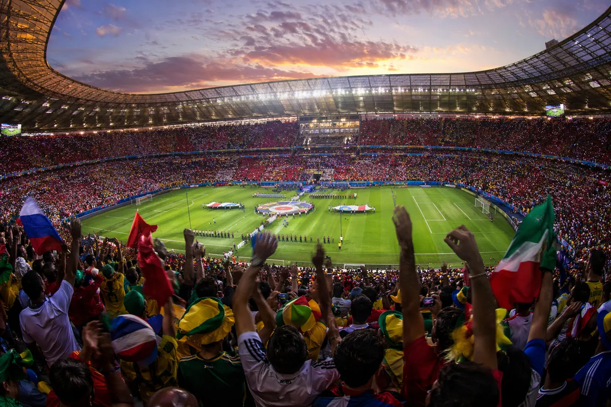 A wide-angle shot of a packed FIFA World Cup football stadium at dusk, vibrant cheering fa