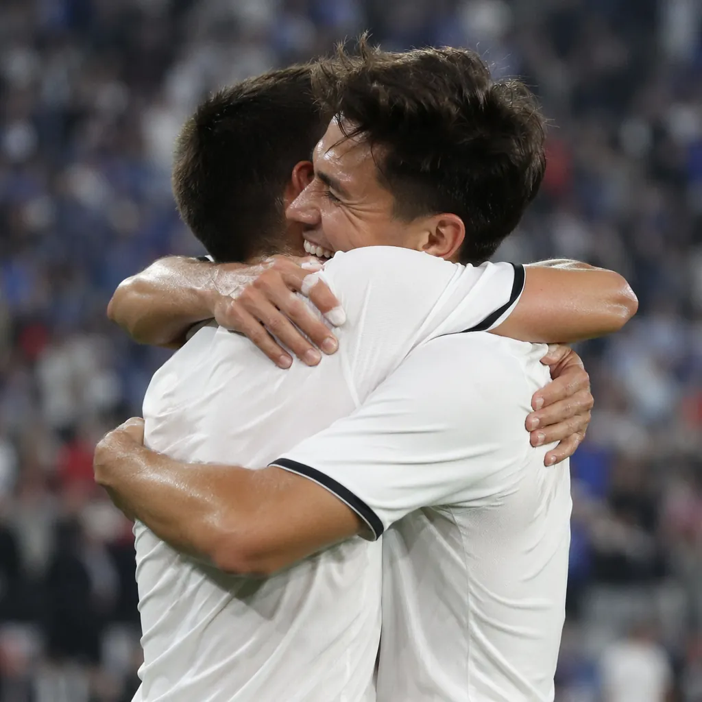 Close-up of generic unbranded soccer players celebrating a draw on the pitch, bl