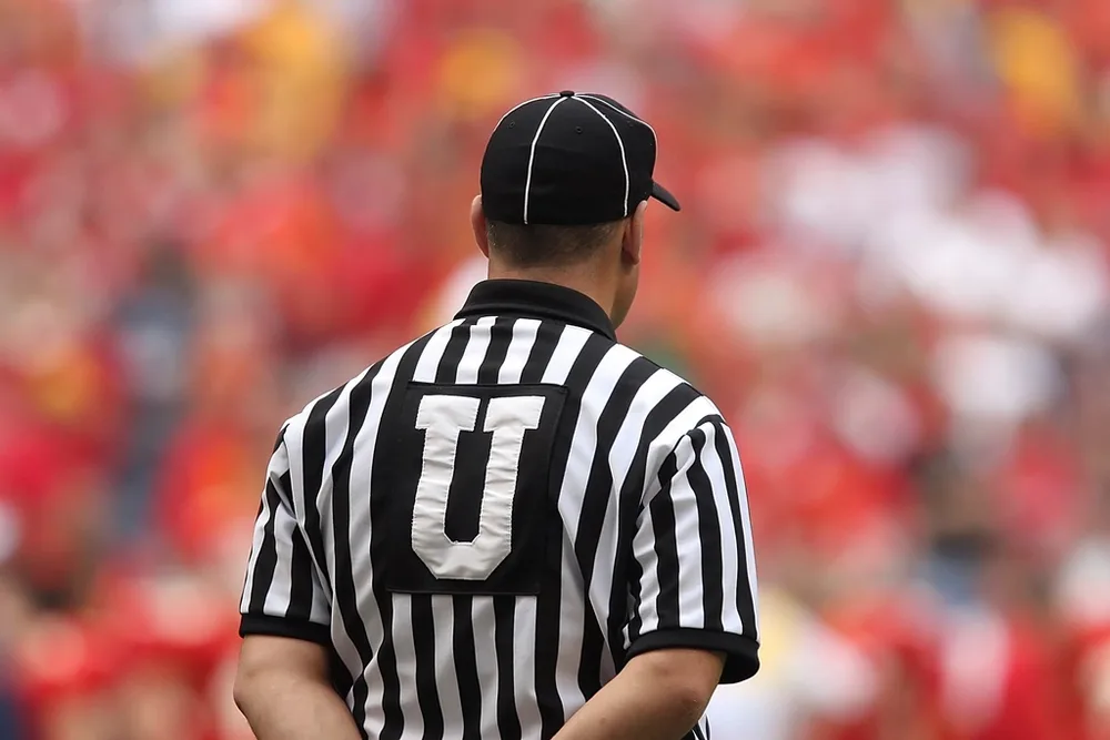 Close up shot of a referee holding a red card on green football field, neutral b
