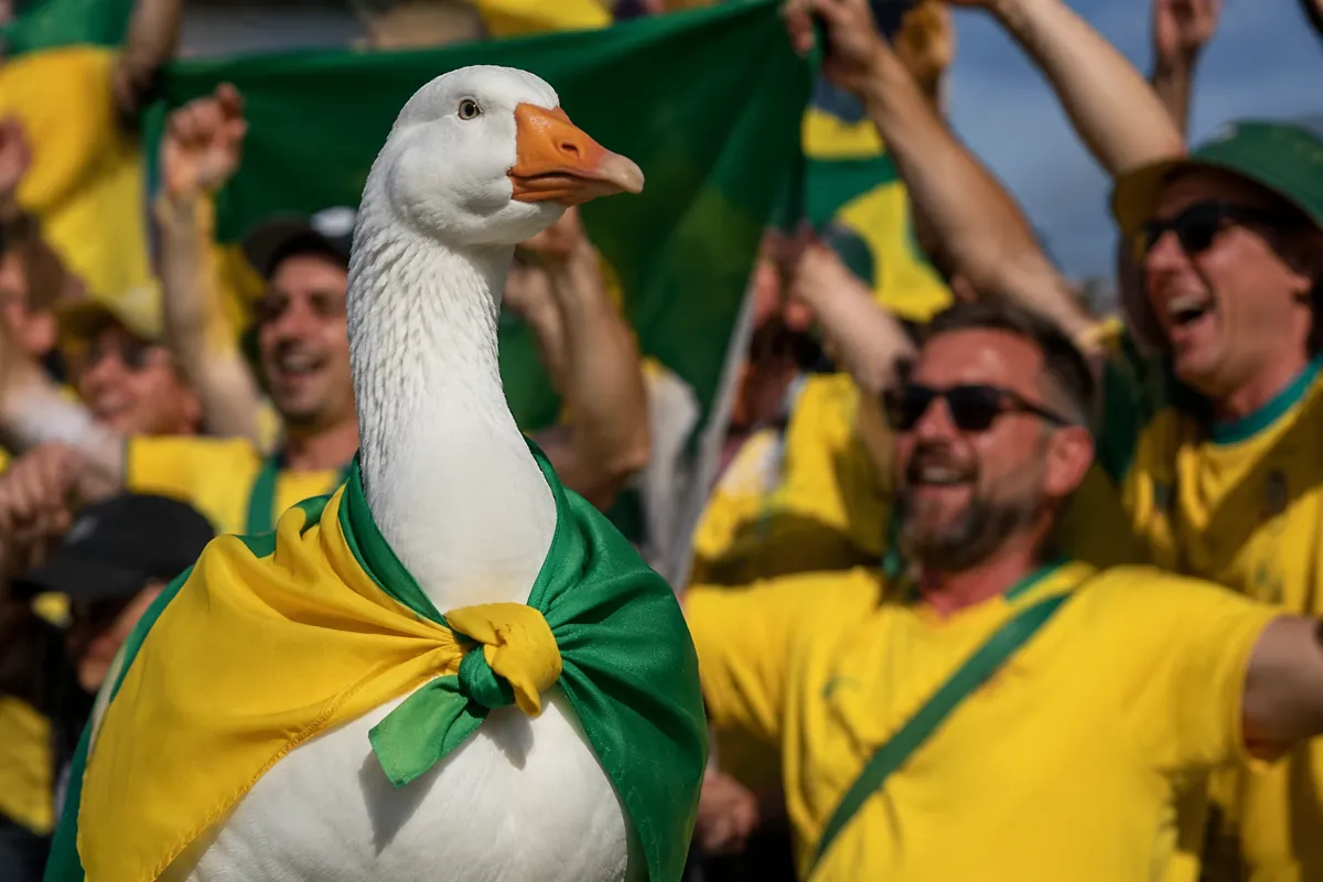 A large white goose wearing a green and yellow fabric shawl standing among cheering footba