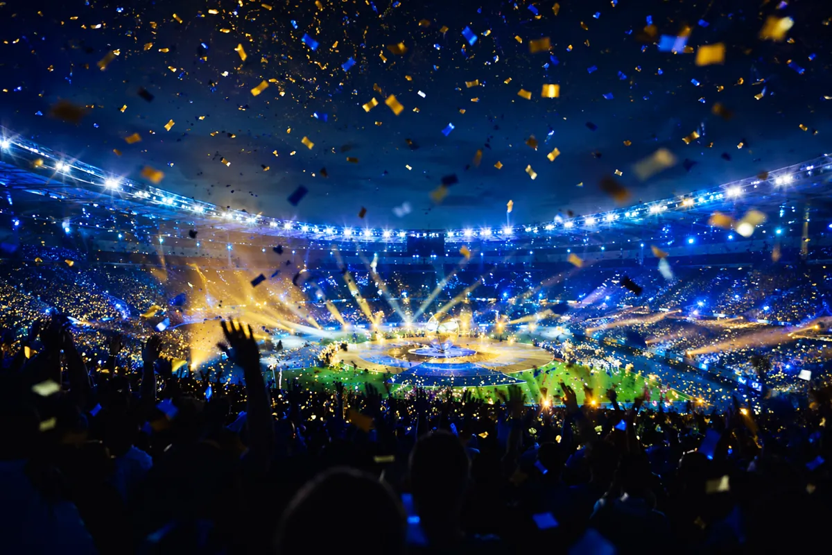 Modern football stadium at night with bright stadium lights, blue and gold confetti fallin