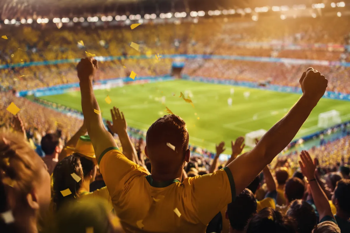 editorial sports news header image, blurred football stadium with cheering fans during wor