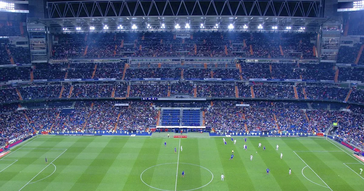 Wide shot of a professional football stadium during a World Cup match, golden sunset light