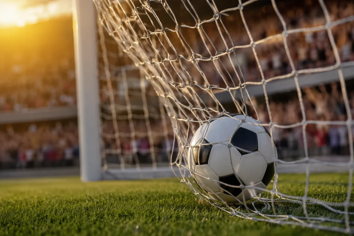 Close-up shot of a soccer ball flying into the bottom corner of a goal net on a well-maint