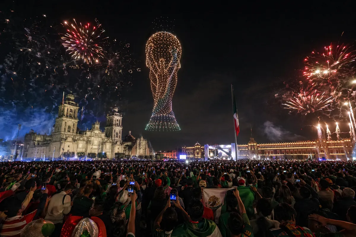 Wide angle night shot of Mexico City Zocalo Square, vibrant fireworks exploding in dark sk
