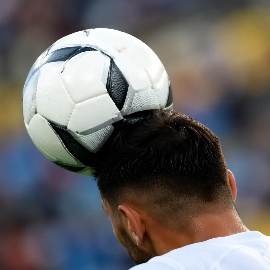 Close up shot of a soccer ball making contact with a player's forehead during a
