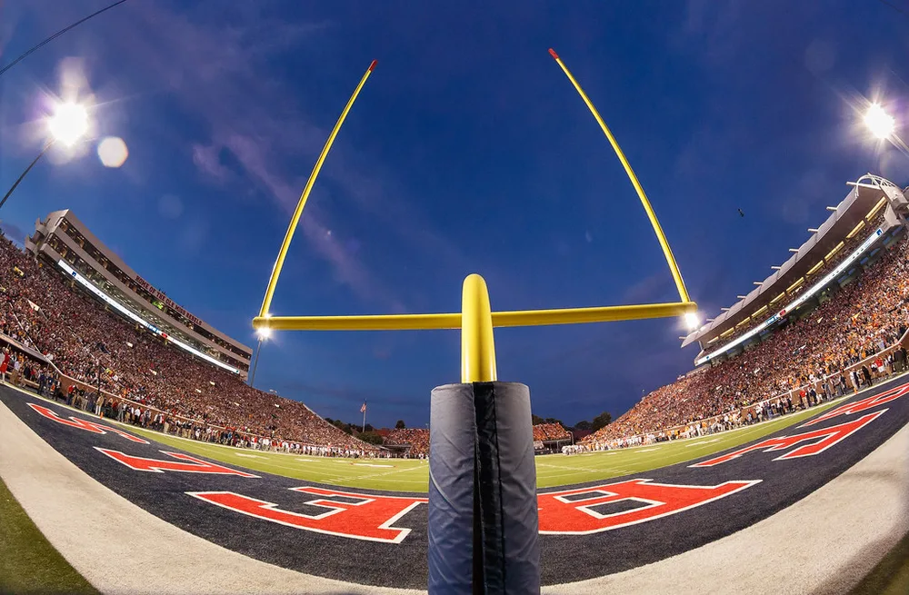 Close up shot of a football rolling near the goal post on a well-maintained gree
